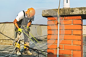 Industrial rope access worker hanging from the building while painting the exterior facade wall. Industrial alpinism concept image