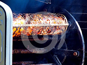Industrial rotating meat grill with big wheels, chain & metal mesh drums to keep meet inside