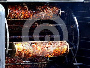 Industrial rotating meat grill with big wheels, chain & metal mesh drums to keep meet inside