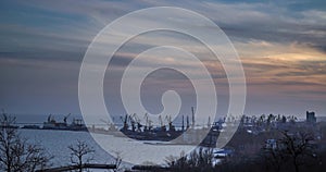 An industrial sea terminal with cargo cranes and railroad containers on sunset. Shore crane lifts freight during