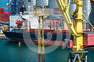 Industrial seaport infrastructure, sea, cranes and dry cargo ship, grain silo and bulk carrier vessel, concept of sea cargo