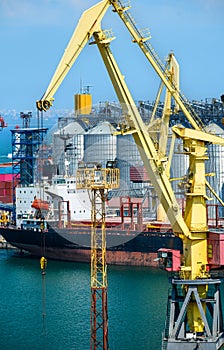 Industrial seaport infrastructure, sea, cranes and dry cargo ship, grain silo and bulk carrier vessel, concept of sea cargo