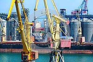 Industrial seaport infrastructure, sea, cranes and dry cargo ship, grain silo, bulk carrier vessel and grain storage elevators,