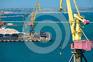 Industrial seaport infrastructure - sea, cranes and minerals, metal and bundles of wire, concept of maritime cargo transportation