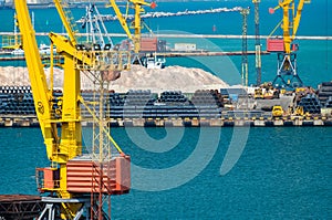 Industrial seaport infrastructure - sea, cranes and minerals, metal and bundles of wire, concept of maritime cargo transportation