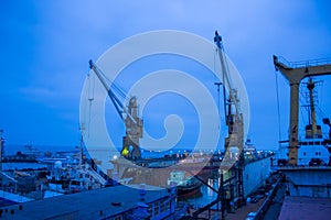 Industrial shipyard at dusk, floating dry dock with ship under repair, cranes standby. Maritime vessel maintenance