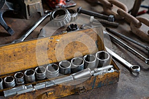 Industrial socket set inside a yellow toolbox on a work bench - Ratchet socket kit next to various hand tools and photo