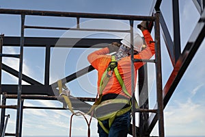 Industrial steel roof truss welders are welding steel with Fall arrestor device for worker with hooks for safety body harness on