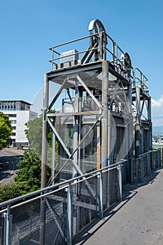 an industrial steel structure on the side of a hill near trees