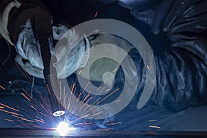 Industrial steel welder in factory. welder with protective mask welding metal and sparks