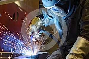 Industrial steel welder in factory. welder with protective mask welding metal and sparks