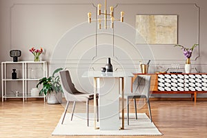 Industrial style, golden pendant light above an exceptional marble table in a trendy dining room interior