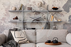 Industrial style of modern apartment with grey design sofa, plants, tea pot, bookstand, pedant lamp, carpet, decoration, pillows photo
