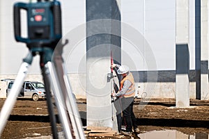 Industrial surveyor on construction site, working with thodolite, gps system and level machine