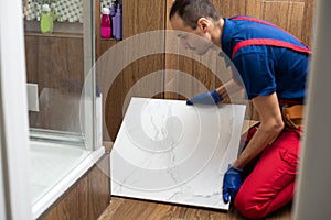 Industrial tiler builder worker installing floor tile at repair renovation work