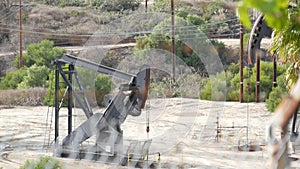 Industrial urban landscape. La Brea Inglewood in Los Angeles. Well pump jack operating behind the fence. Drilling rig