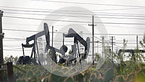 Industrial urban landscape. La Brea Inglewood in Los Angeles. Well pump jack operating behind the fence. Drilling rig