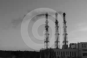 Industrial view - Thermal power station with pipes in the city near the forest. From the chimneys smoke into the sky. ecology con