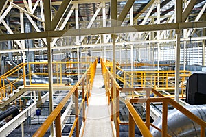 Industrial walk way with yellow handrail and steel structure roof inside factory
