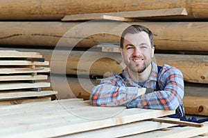 Industrial warehouse of a sawmill, an employee puts his hands on the finished products at the sawmill in the open air.