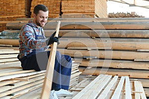 Industrial warehouse of a sawmill, an employee puts his hands on the finished products at the sawmill in the open air.