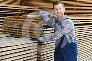 Industrial warehouse of a sawmill, an employee puts his hands on the finished products at the sawmill in the open air.