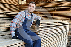 Industrial warehouse of a sawmill, an employee puts his hands on the finished products at the sawmill in the open air.