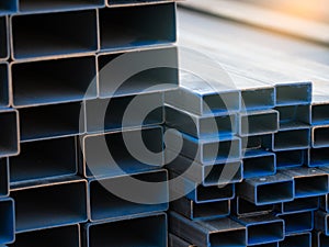 Industrial warehouse stock of rectangular metal pipes for building and construction supplies. Stack of steel pipes. Iron materials