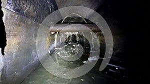Industrial wastewater and urban sewage flowing throw dark underground sewer concrete tunnel