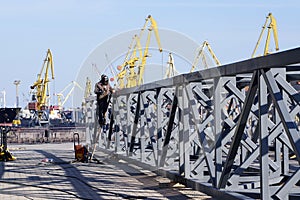 Industrial Welder With Torch and Protective Helmet in a seaport welding big cross construction