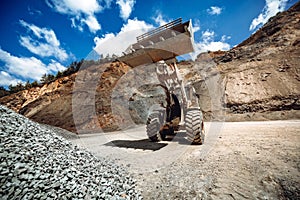 Industrial wheel loader working on construction site. Industrial machinery loading and transporting gravel