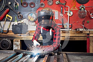 Industrial work, welder works with metal, sparks and fire on background of workplace