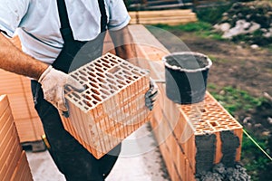 Industrial worker building exterior walls laying bricks in cement. Detail of worker with tools and concrete