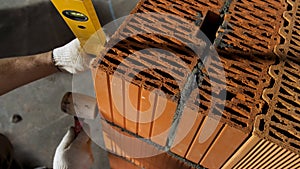 Industrial worker building exterior walls, using hammer and level for laying bricks in cement. Stock footage. Detail of