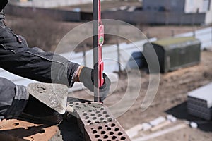 industrial worker building exterior walls, using level for laying bricks