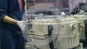 Industrial worker collecting drums for domestic washing machine at factory