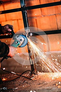 Industrial worker cutting steel with angle grinder