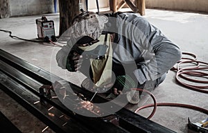 Industrial Worker at the factory welding closeup. Electric wheel grinding on steel structure in factory.