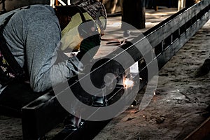 Industrial Worker at the factory welding closeup. Electric wheel grinding on steel structure in factory.