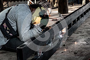 Industrial Worker at the factory welding closeup. Electric wheel grinding on steel structure in factory.