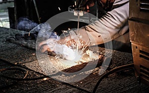 Industrial Worker at the factory welding closeup. Electric wheel grinding on steel structure in factory.