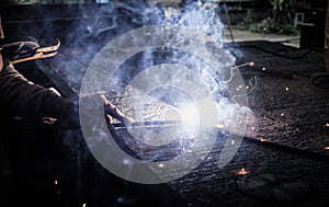 Industrial Worker at the factory welding closeup. Electric wheel grinding on steel structure in factory.