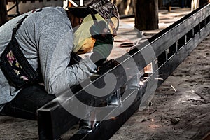 Industrial Worker at the factory welding closeup. Electric wheel grinding on steel structure in factory.