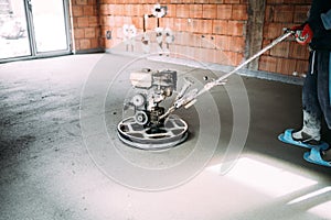Industrial worker finishes concrete screed with trowel machine