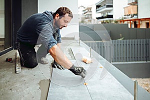 Industrial worker, handyman installing big ceramic tiles on bathroom walls.