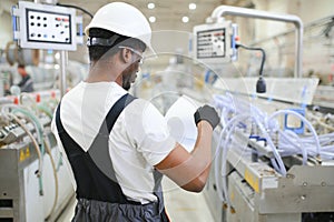 Industrial worker indoors in factory. Young technician with white hard hat