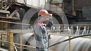 Industrial worker inspects machinery at manufacturing plant.