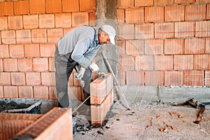 industrial worker installing brick masonry on interior wall with trowel putty knife