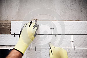 industrial worker installing small ceramic tiles in bathroom during renovation works