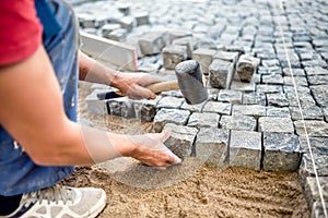Industrial worker installing stone blocks on pavement, street or sidewalk construction works